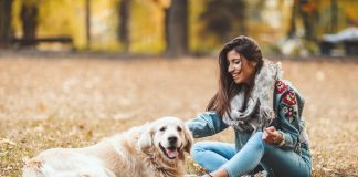 Eine Frau streichelt glücklich ihren Golden Retriever. Grundkenntnisse über Hunde hat sie beim Hundeführerschein oder Sachkundenachweis gelernt.