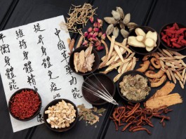 Traditionelle Chinesische Medizin: Eine Schrifttafel, Akupunkturnadeln und medizinische Kräuter.