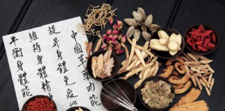 Traditionelle Chinesische Medizin: Eine Schrifttafel, Akupunkturnadeln und medizinische Kräuter.