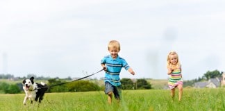Zwei junge Kinder jagen hinter einem Hundeweplen her.